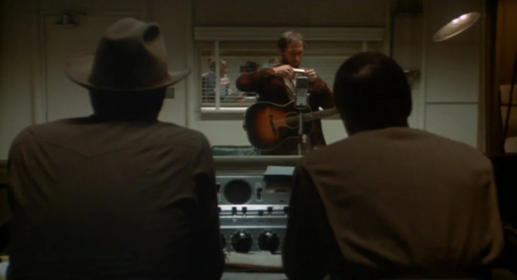 Bound For Glory (1976) movie still: medium — A recording studio control room contains a large vintage mixing console and acoustic glass. A man with…