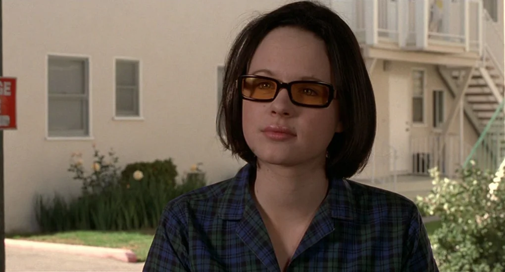 Ghost World (2001) movie still: medium — A light-colored stucco apartment building exterior features a concrete stairway and grassy landscaping. A…