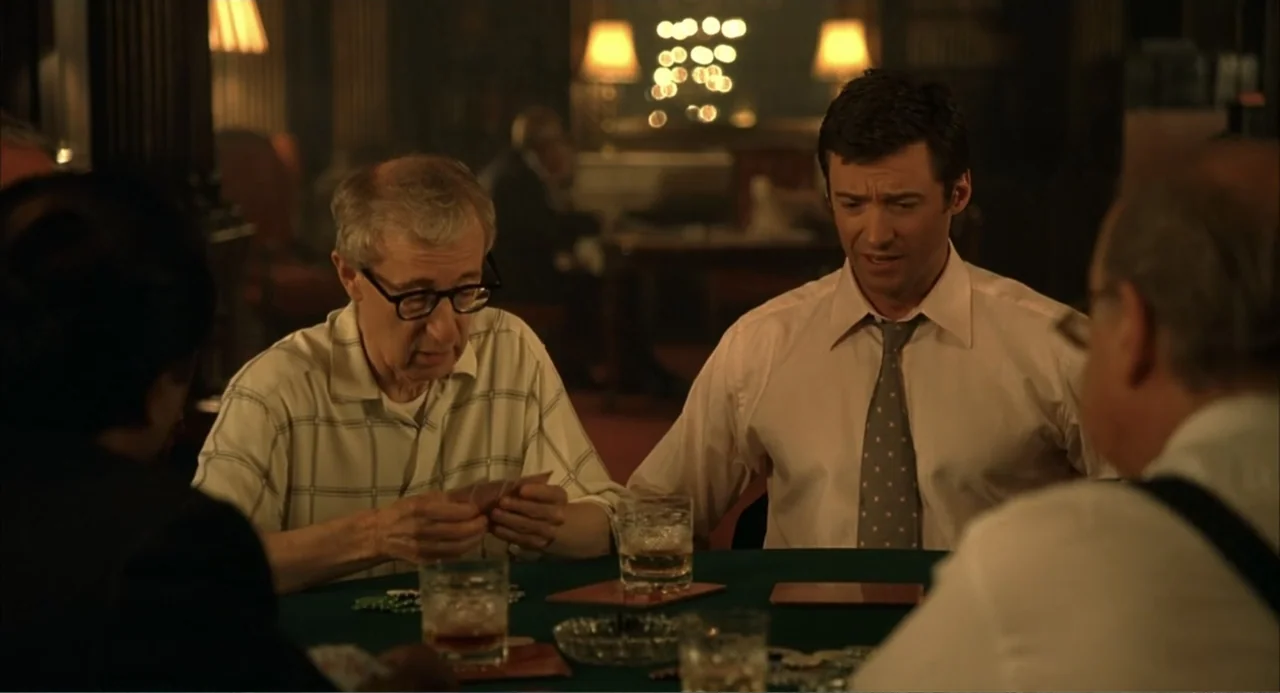 Scoop (2024) movie still: medium — A dimly lit room features a green table where several men play cards together. One elderly man examines his hand…