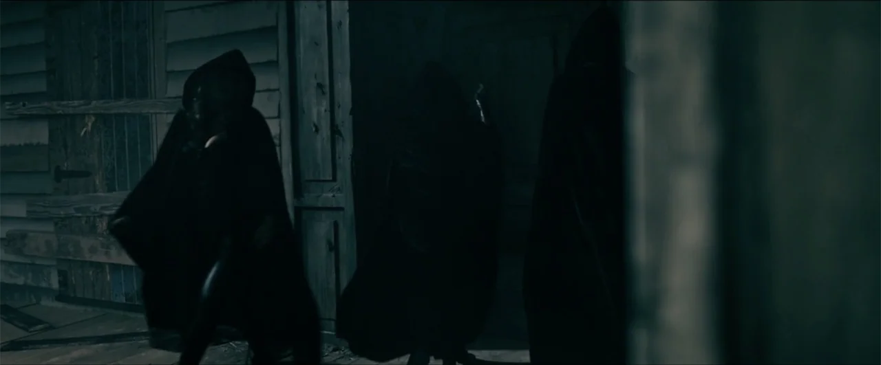 Jeepers Creepers: Reborn (2022) movie still: medium — A wooden building exterior features weathered siding and dark doorways under dim night…