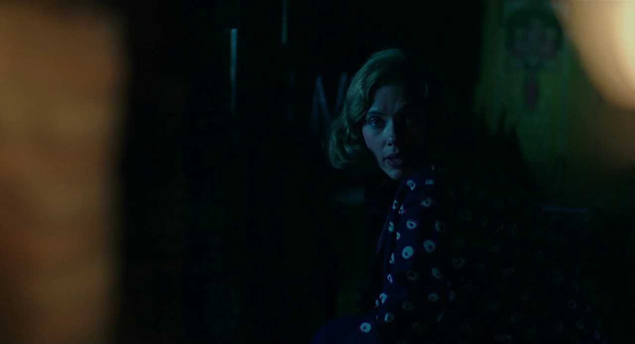 Jojo Rabbit (2019) movie still: medium — A dimly lit room with heavy shadows hides the surrounding wall details from view. A woman with a blonde bob…