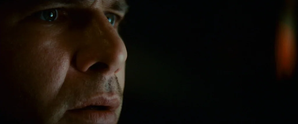 Blade Runner (1982) movie still: closeup — A man's face is illuminated in a dark room by a nearby light source. He stares forward while his features…