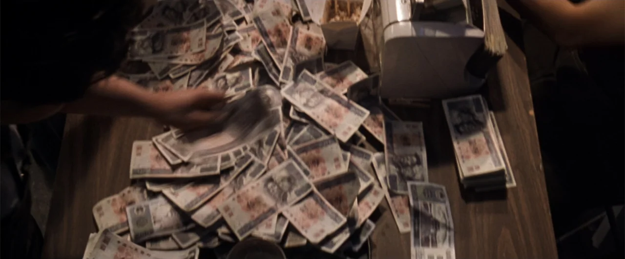 Lethal Weapon 4 (1998) movie still: medium — A wooden table is covered in a large quantity of Japanese currency notes. A person sorts the money next…