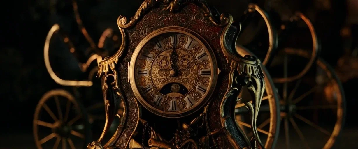 Beauty and the Beast (2017) movie still: closeup — An ornate antique clock face is crafted from dark metal and aged brass filigree. The clock is…