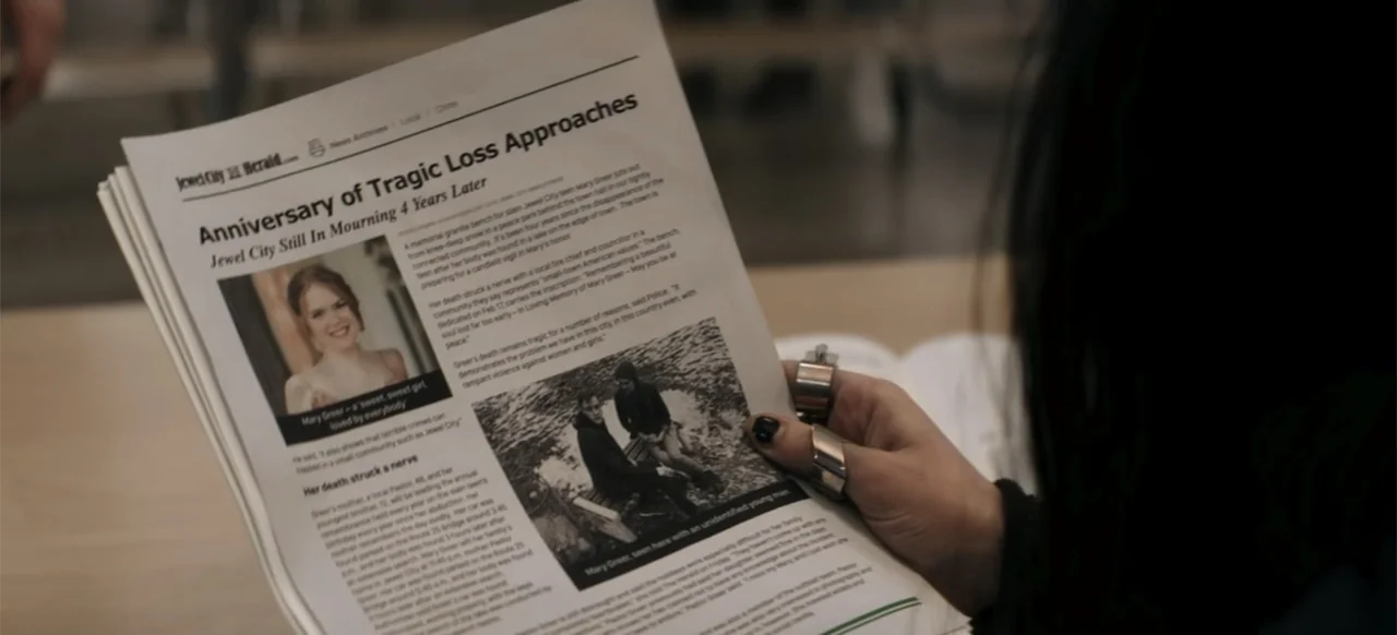I Still See You (2018) movie still: closeup — A person holds a newspaper featuring a headline about a memorialized murder victim. The subject…