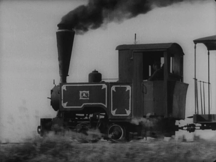 Sanshiro Sugata (1943) movie still: wide — A small vintage steam engine moves along a track under a light sky. The locomotive features a prominent…