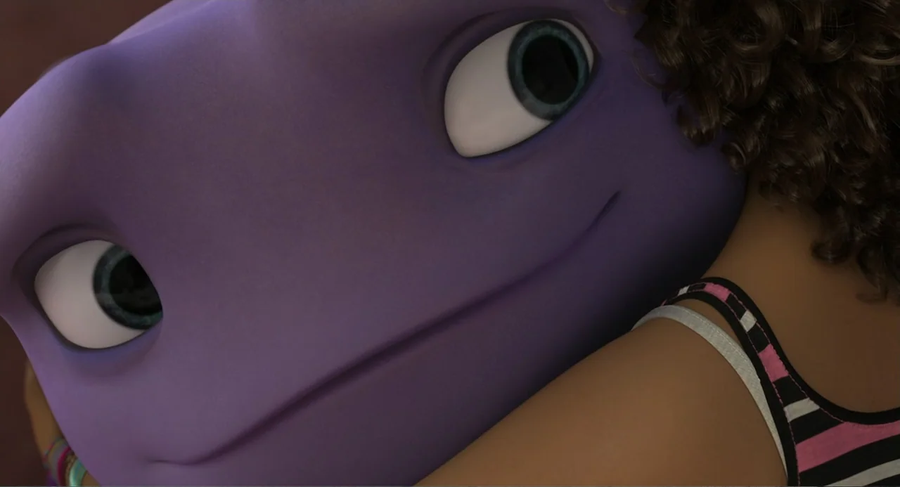 Home (2015) movie still: closeup — A close-up of a purple alien hugging a young child. The child's shoulder and hair are visible against the alien's…