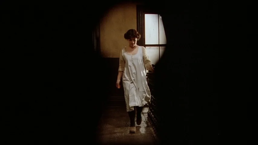 Once Upon A Time In America (1984) movie still: fullbody — A dimly lit indoor hallway with dark walls and a singular window at the end. A woman in a…