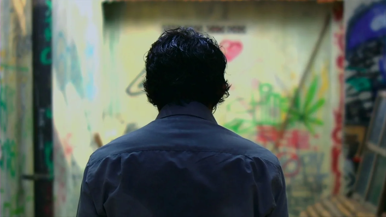 Merantau (2009) movie still: medium — A narrow passage with concrete walls heavily covered in multi-colored graffiti. A person stands with their…