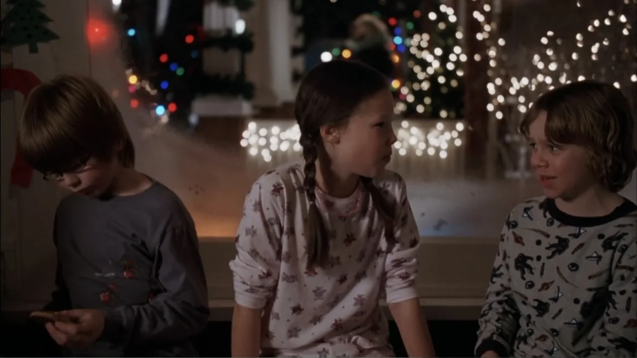 Just Friends (2005) movie still: medium — Three children in pajamas sit in a home at night near a large window. They are gathered together, with the…
