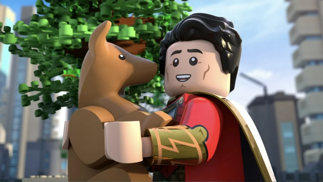 LEGO DC: Shazam! Magic and Monsters (2020) movie still: medium — A Lego-style superhero figure stands outdoors near a green tree with city buildings…