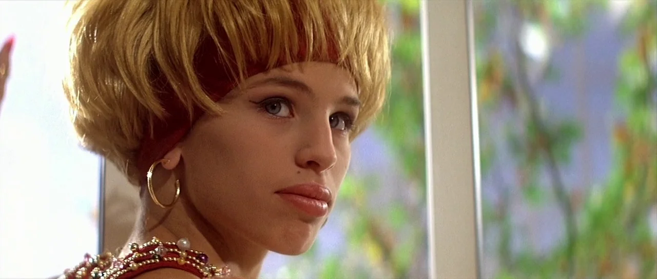 Léon: The Professional movie still: closeup — A bright interior space features a window looking out onto blurred green foliage. A young woman with a…