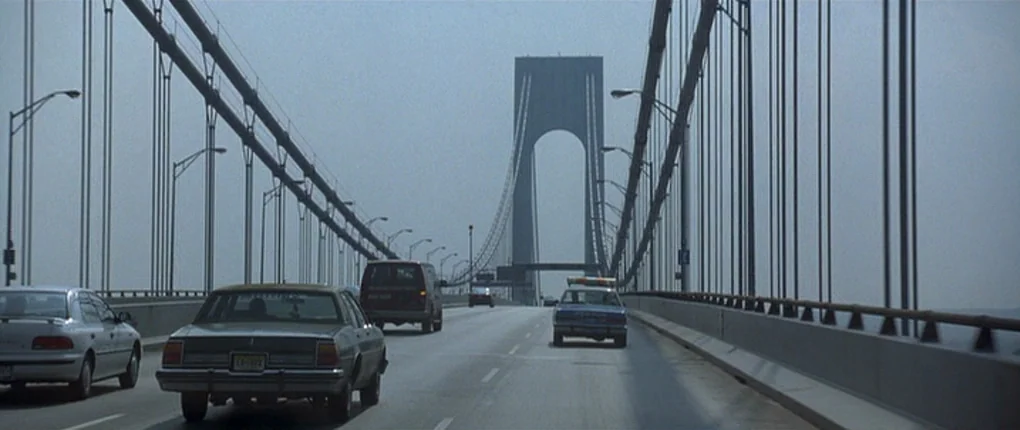The Usual Suspects movie still: wide — The Verrazzano-Narrows Bridge stretches across a misty bay on a cloudy afternoon. Several 1990s-era…
