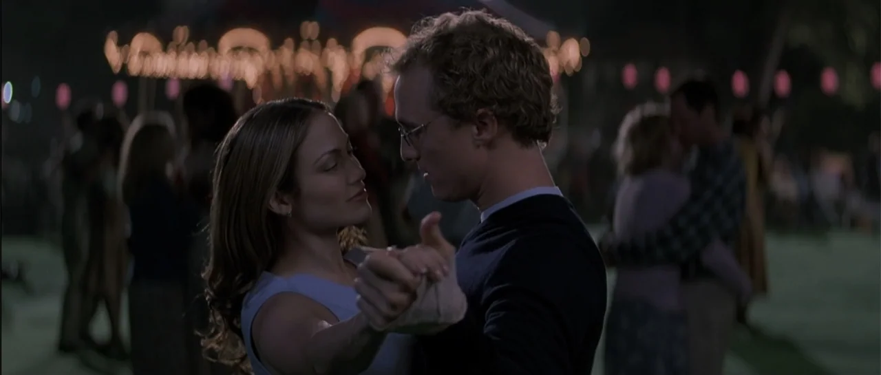 The Wedding Planner (2001) movie still: medium — An outdoor night event features blurred string lights across the dark background. A man and a woman…