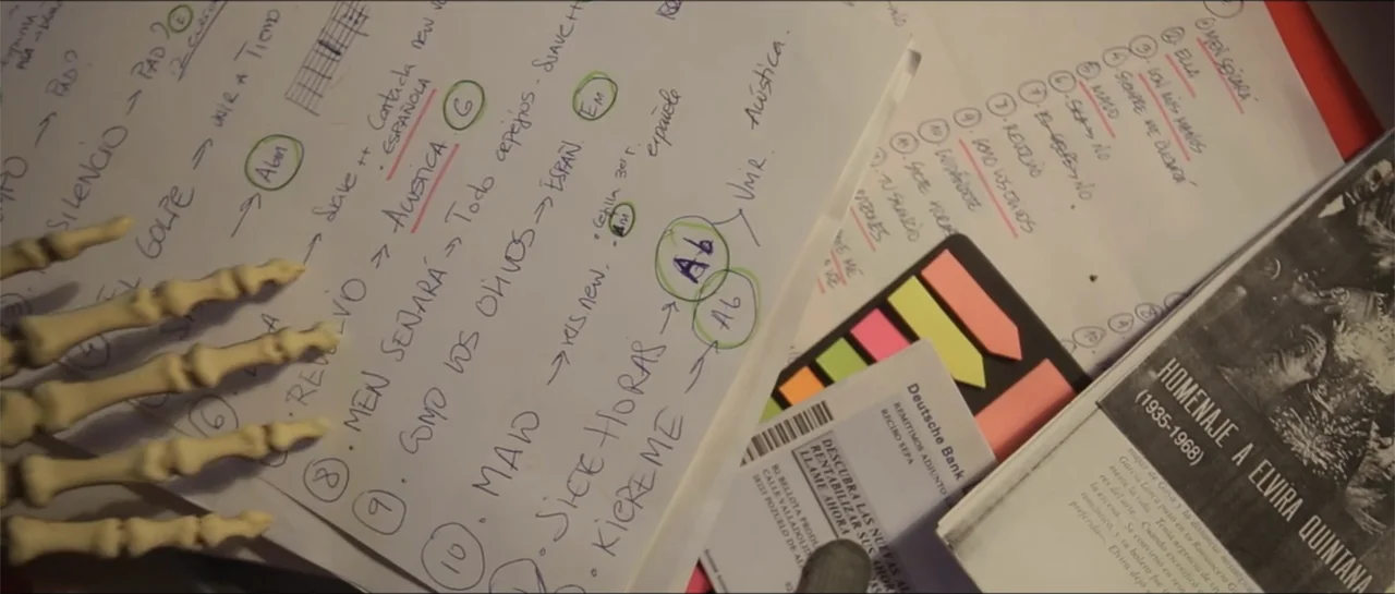 10 Years with Bebe (2016) movie still: closeup — A desk surface is cluttered with handwritten musical notes and a commemorative pamphlet. A plastic…