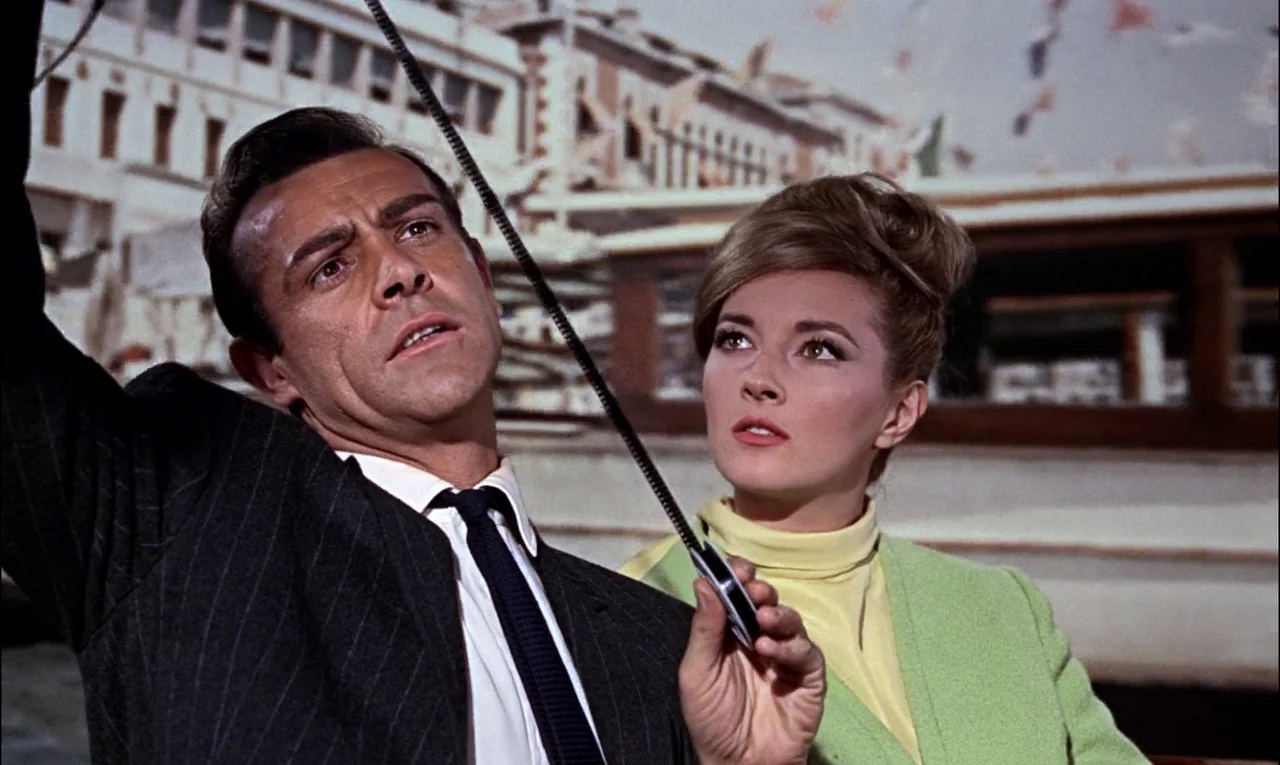 From Russia With Love (1963) movie still: medium — A boat deck featuring a backdrop of blurry historical buildings under a bright sky. A man and…