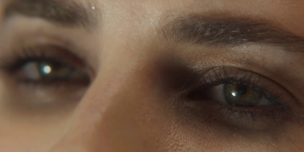 Paradise Hills (2019) movie still: closeup — A close extreme portrait focuses on the eyes of a young woman. The skin texture is visible with fine…