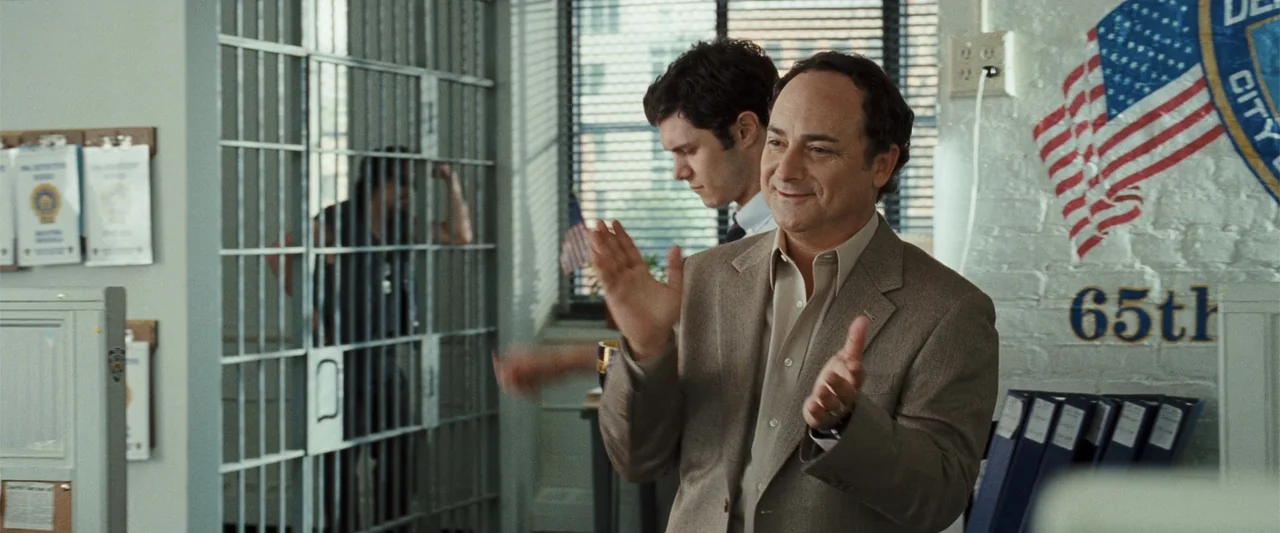 Cop Out (2010) movie still: medium — A police squad room interior with metal bars of a holding cell in the background. Two men stand in the…