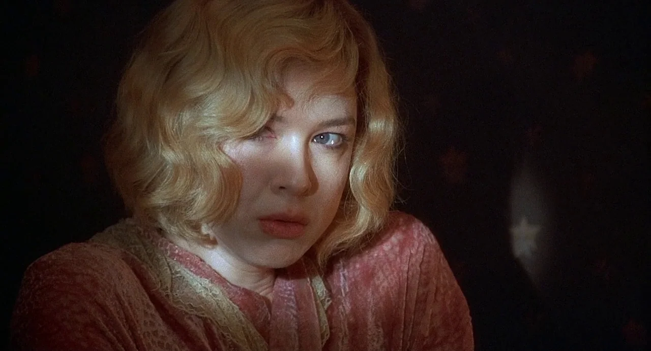 Chicago (2002) movie still: closeup — A dark bedroom with star-patterned wallpaper dimly illuminated in the background. A blonde woman in a pink…