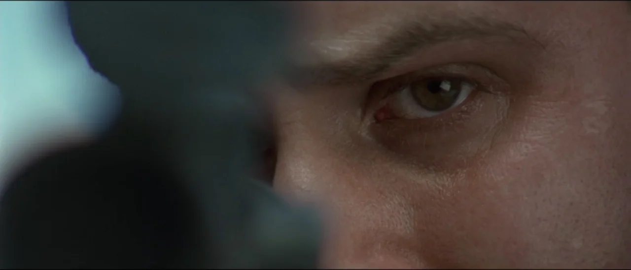 The Peacemaker (1997) movie still: closeup — A close view of a man's face indoors with soft lighting on his skin. He gazes steadily toward the side…