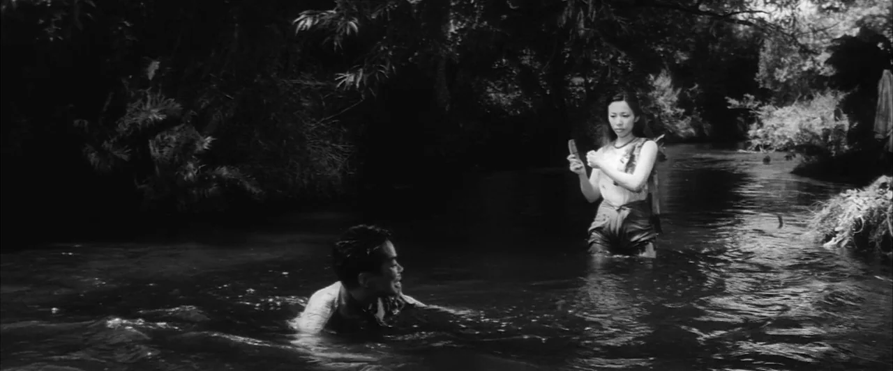 The Human Condition III: A Soldier’s Prayer (1961) movie still: medium — A dark river runs through a dense, tree-covered tropical forest with heavy…