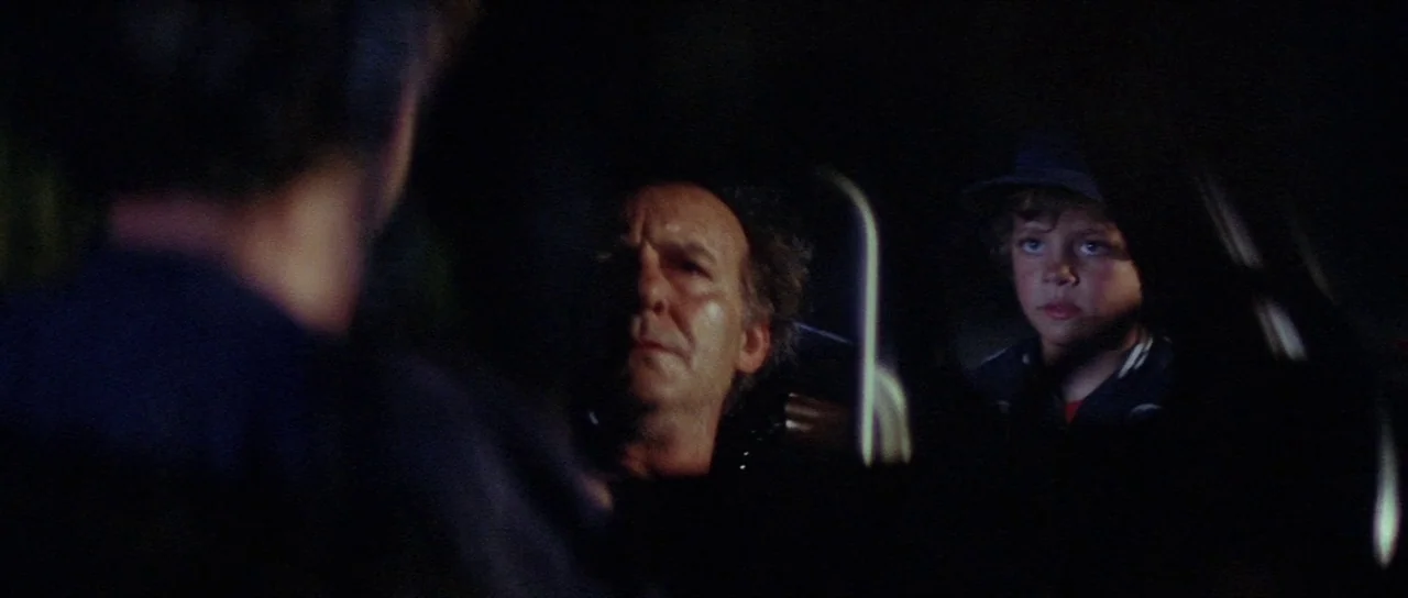 The Funhouse (1981) movie still: medium — An interior shot of a car at night showing three people inside. An older man sits in the driver seat while…