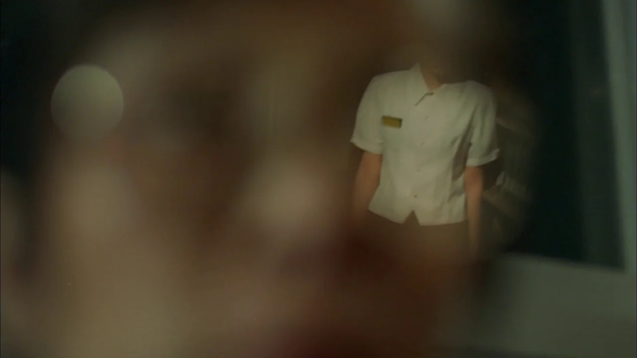 Whispering Corridors (1998) movie still: medium — A dimly lit indoor space with a figure visible in the background. The foreground is heavily…