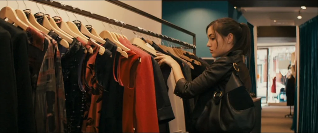 The Girlfriend Experience (2009) movie still: medium — A well-lit clothing boutique features rows of garments hanging on metal racks. A woman…