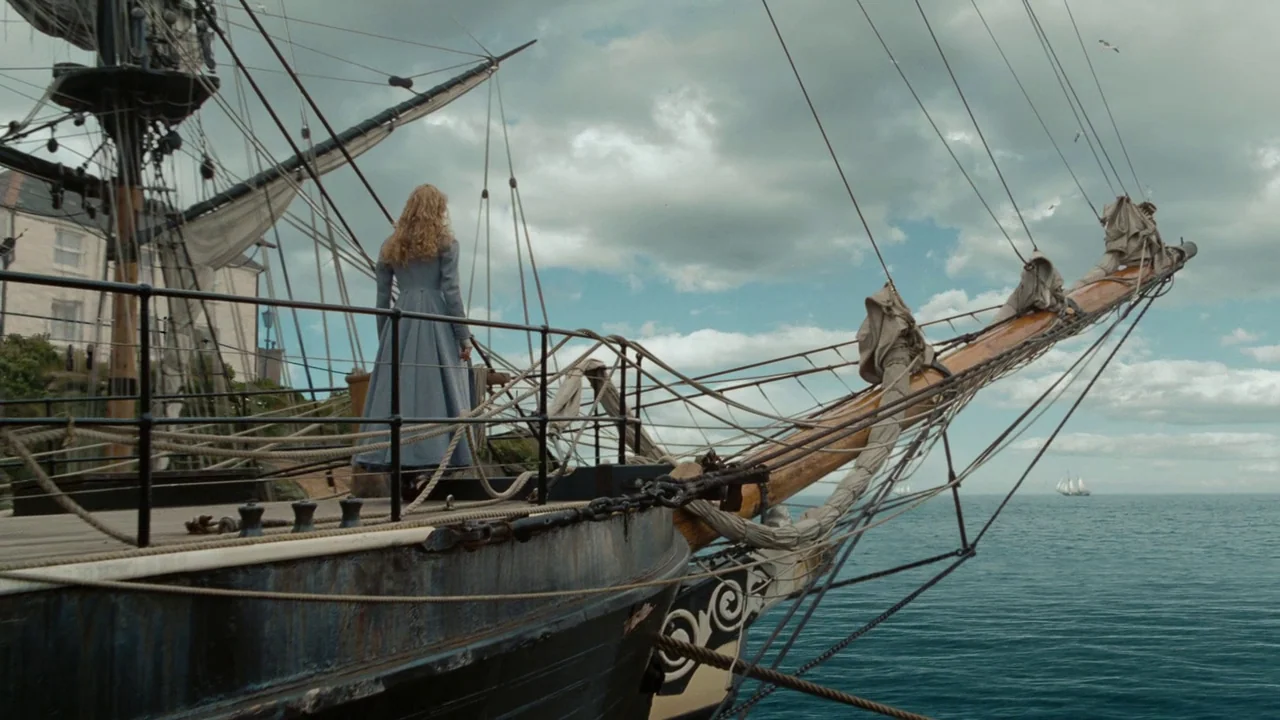 Alice in Wonderland (2010) movie still: wide — The bow of a large wooden sailing ship glides across a calm ocean surface. A woman stands near the…