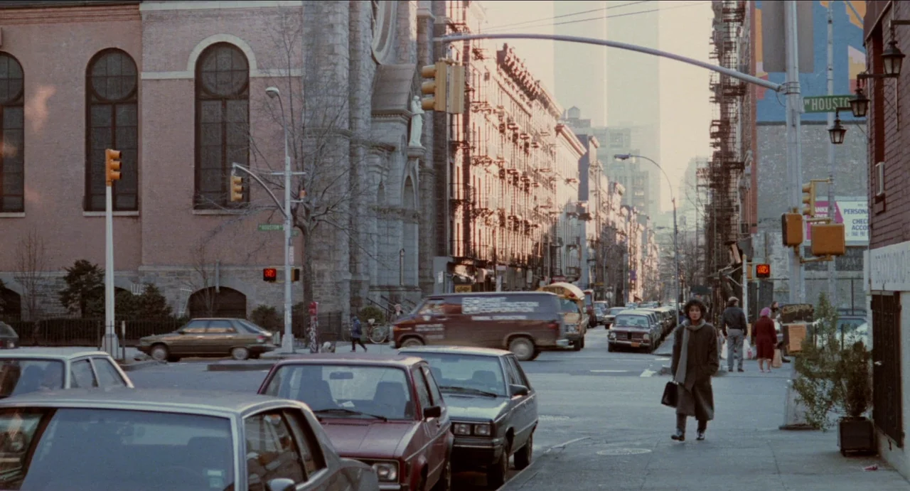 Moonstruck (1987) movie still: wide — A busy New York City street intersection features a stone church and brownstone apartment buildings.…