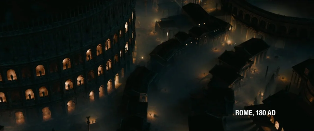 Man with No Past (2025) movie still: establishing — An aerial perspective shows a vast stone amphitheater looming over a dense ancient city. Thick…