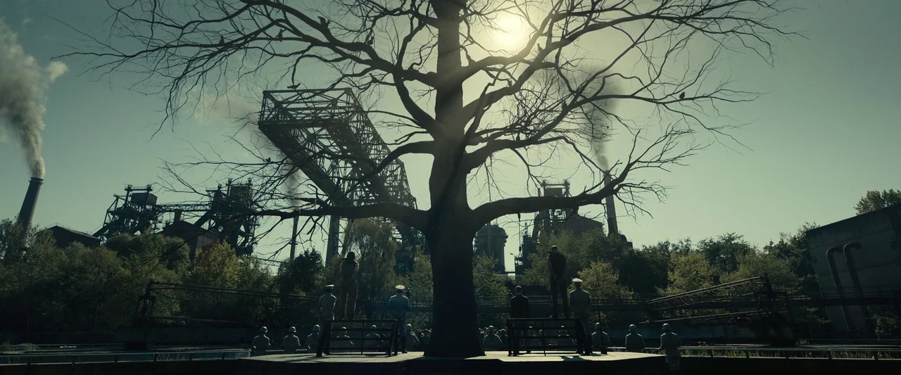 The Hunger Games: The Ballad of Songbirds & Snakes (2023) movie still: wide — A desolate industrial area features a large, bare-branched tree…