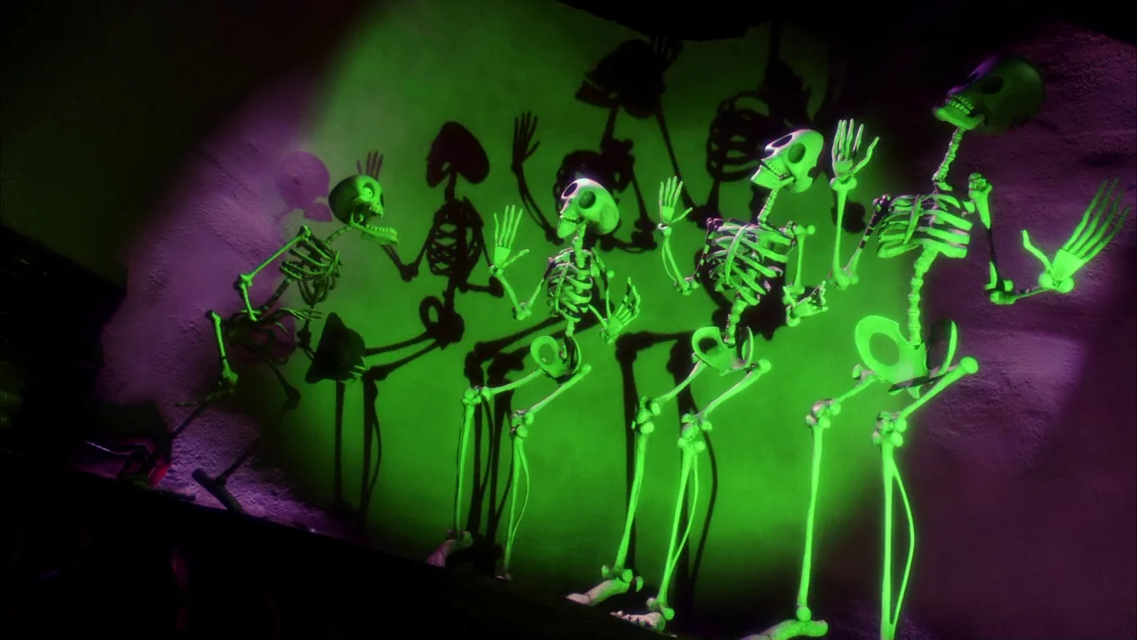 The Corpse Bride (2005) movie still: medium — Four animated skeletons dance in front of a textured purple wall under green light. Their movements…