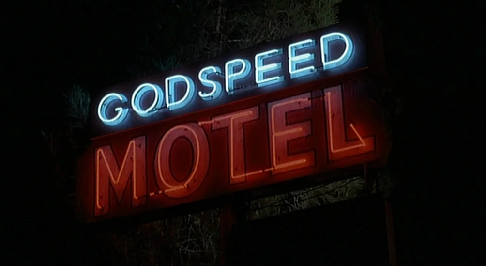 Near Dark (1987) movie still: closeup — A rectangular motel sign with glowing neon letters mounted against a dark night sky. The sign reads GODSPEED…