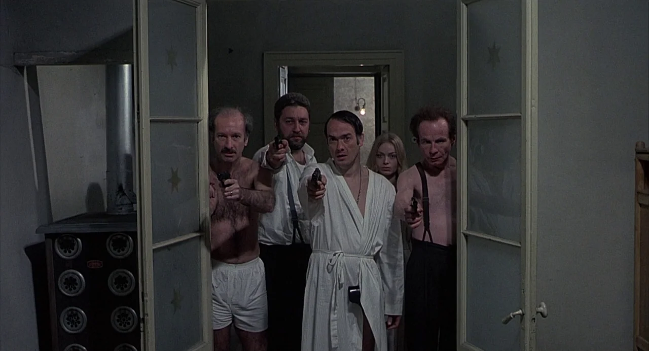 Salò, or the 120 Days of Sodom (1975) movie still: medium — A dark hallway features a doorway with glass panels containing gold star decals. Four…