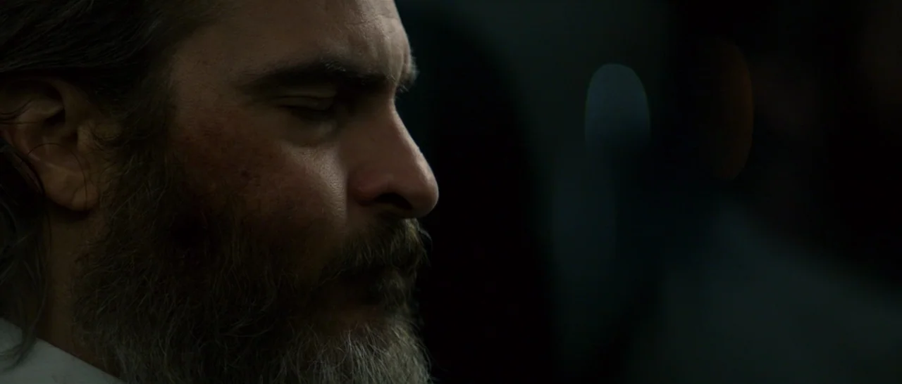 You Were Never Really Here (2017) movie still: closeup — A man stands in a dark environment with his eyes closed. The side profile of his face is…
