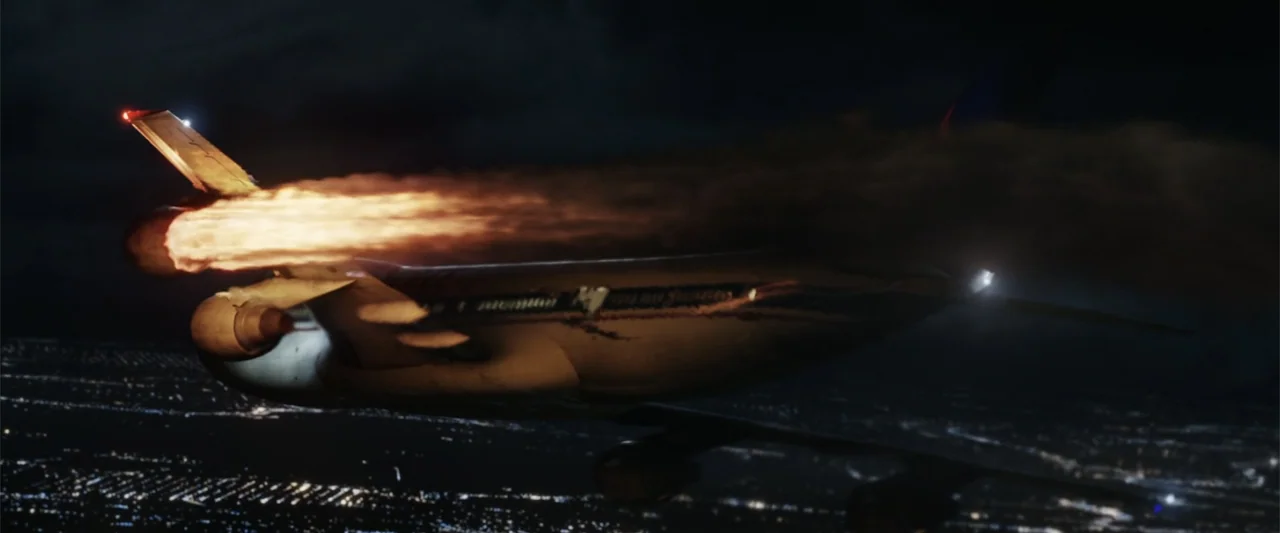 Final Destination 5 (2011) movie still: wide — A damaged airliner streaks through the dark night sky above a distant glowing city. A massive orange…
