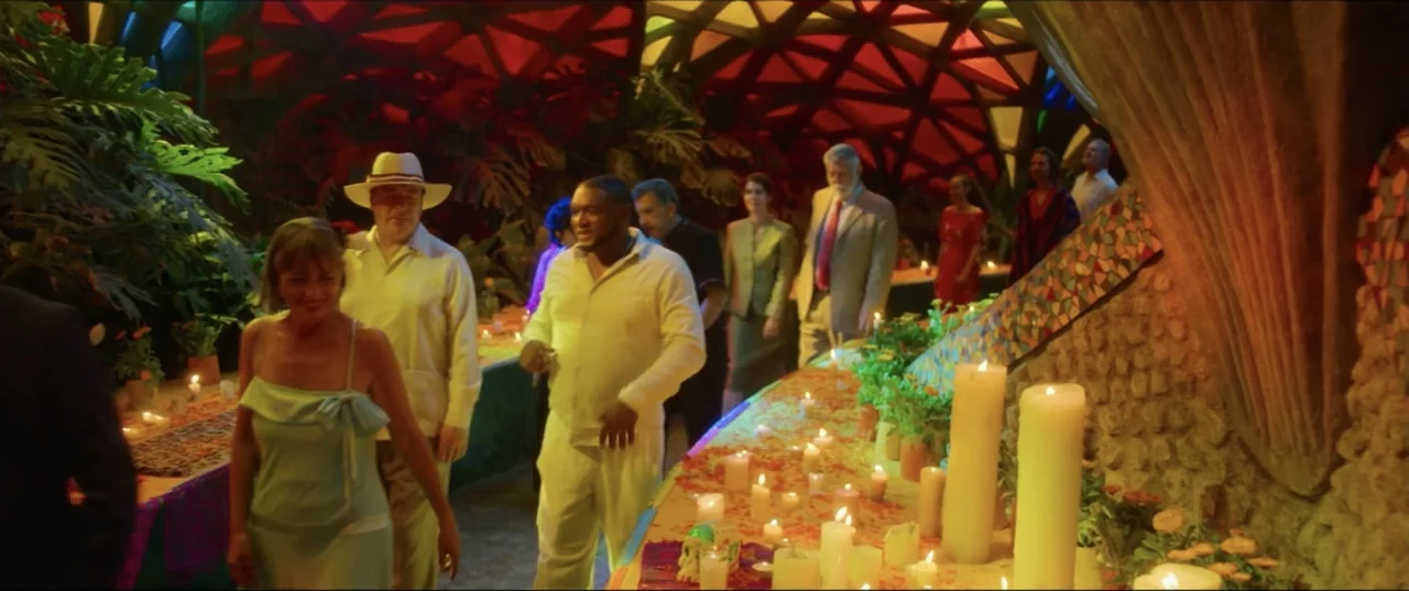Can't Quit Mom (2022) movie still: medium — A dimly lit indoor space features a vaulted ceiling structure with large tropical plants. People walk…