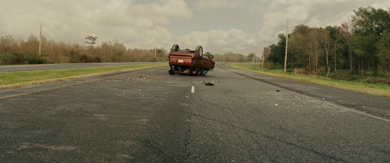 Midnight Special (2016) movie still: wide — An asphalt road runs through a flat, rural landscape with sparse trees and utility poles. A maroon SUV…