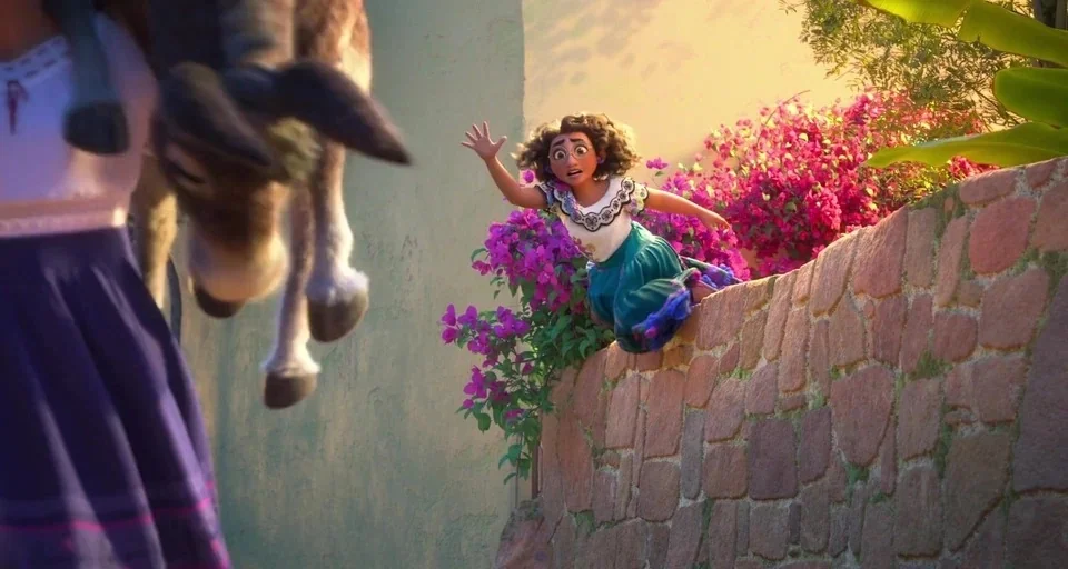 Encanto (2021) movie still: medium — A stone wall overgrown with bright pink bougainvillea flowers stands in an alleyway. A young woman with curly…