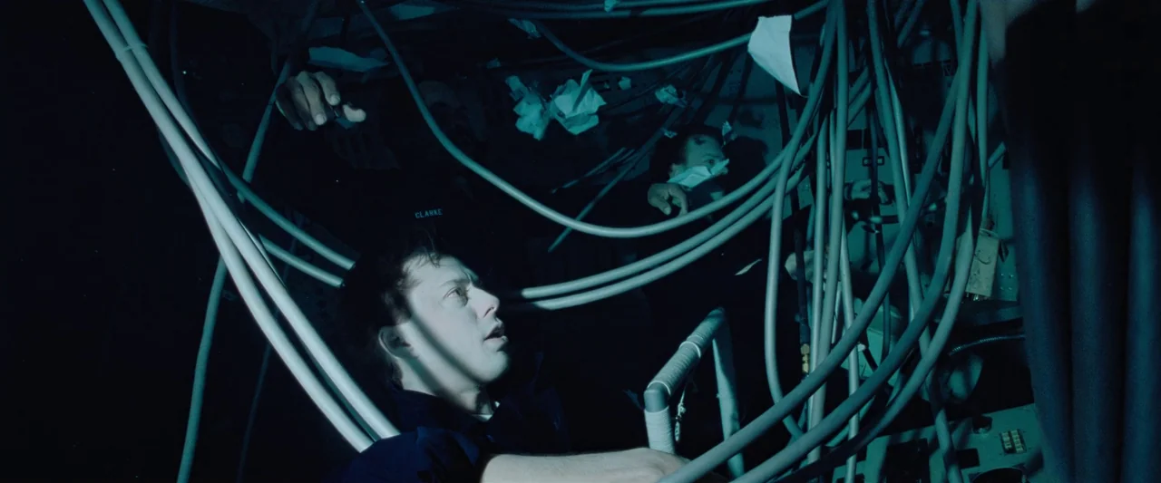 The Abyss (1989) movie still: medium — The interior of a cramped spacecraft is filled with thick, trailing bundles of cables. A man looks upward…