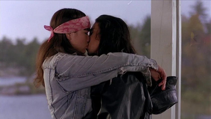 Dance Me Outside (1994) movie still: medium — An outdoor covered space near a body of water overlooks trees in the distance. Two young people in…