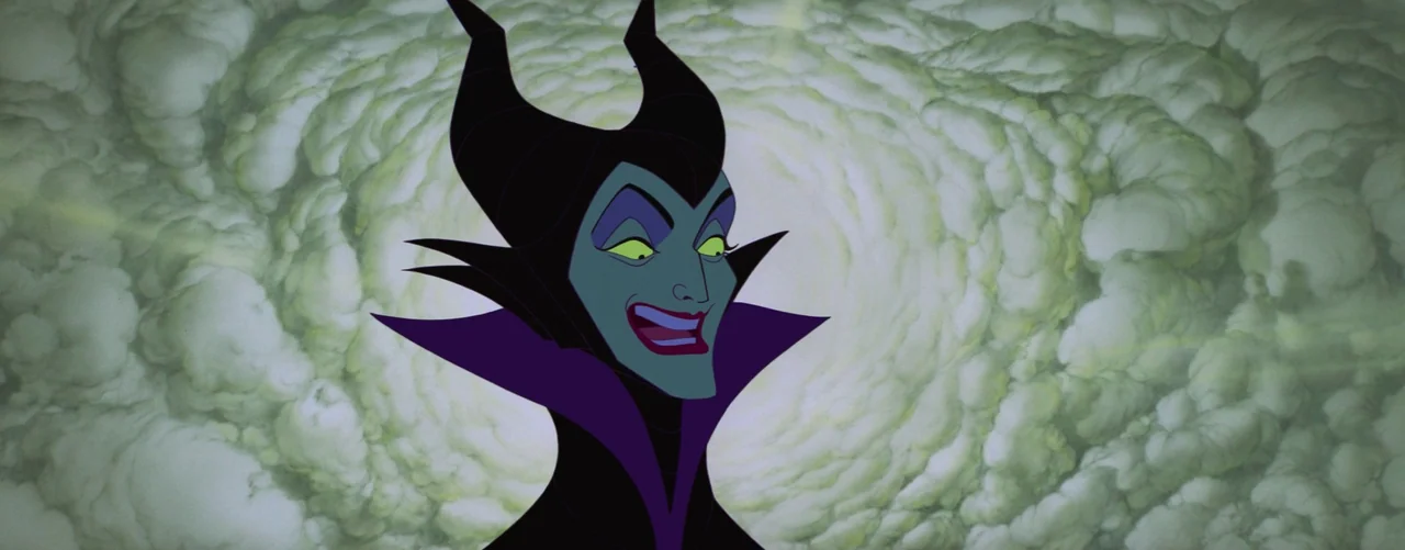 Sleeping Beauty (1959) movie still: closeup — A character with a black horned headdress is centered against swirling pale green clouds. The figure…