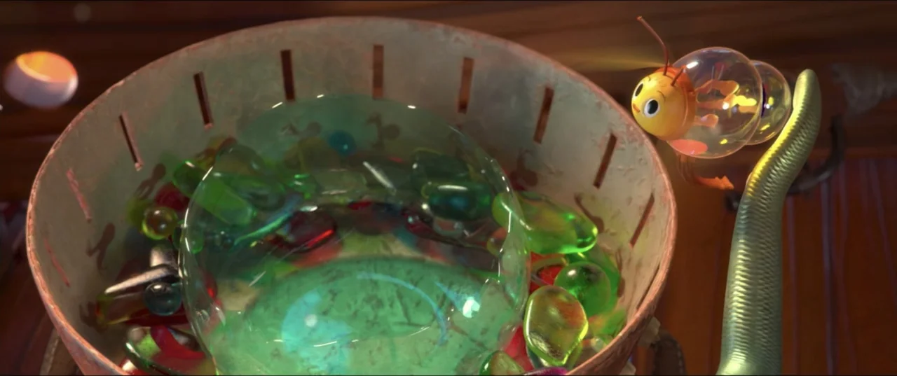 Scarygirl (2023) movie still: medium — A light-colored woven basket contains a collection of translucent green and red glass stones. A small, round,…