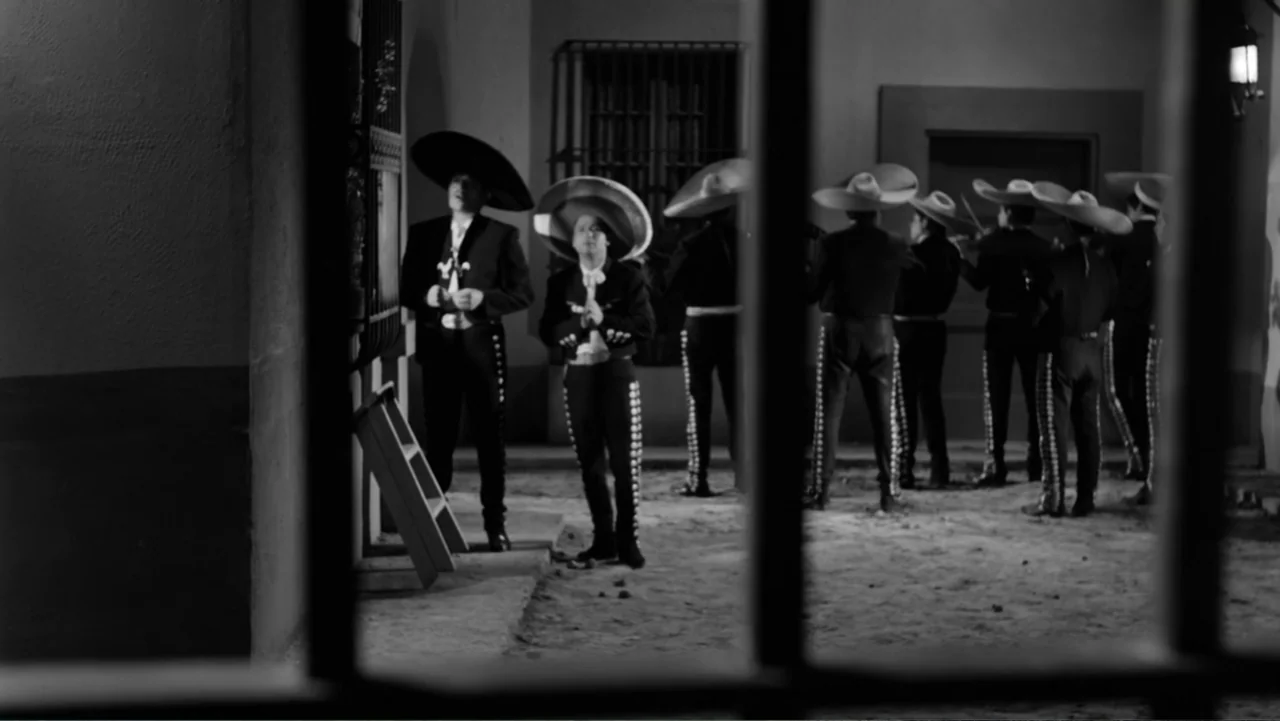 Escuela para solteras (1965) movie still: fullbody — A courtyard at night seen through iron bars featuring a group of mariachi musicians. The men…