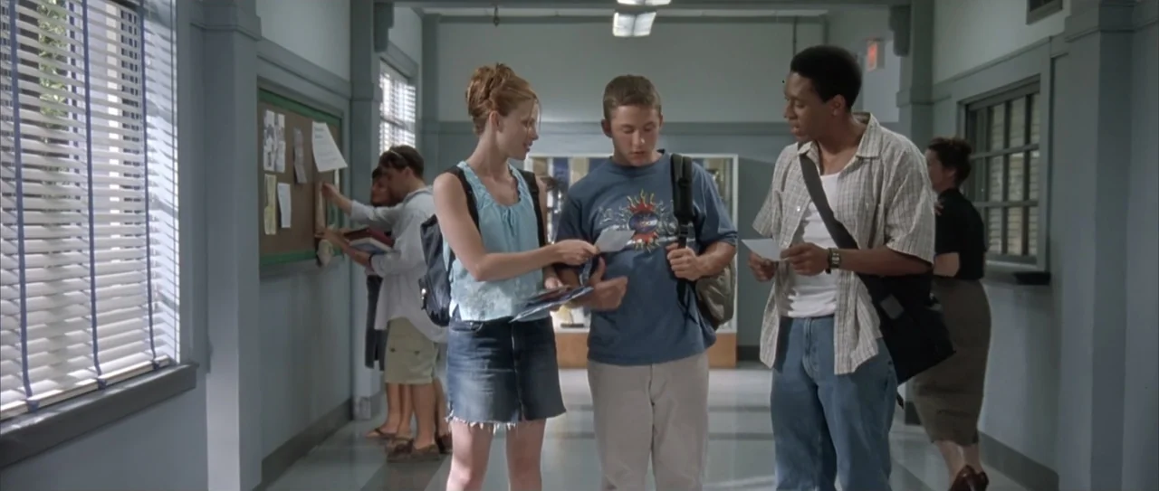 A Walk to Remember (2002) movie still: fullbody — A school corridor features grey walls, tiled floors, and windows with white horizontal blinds.…