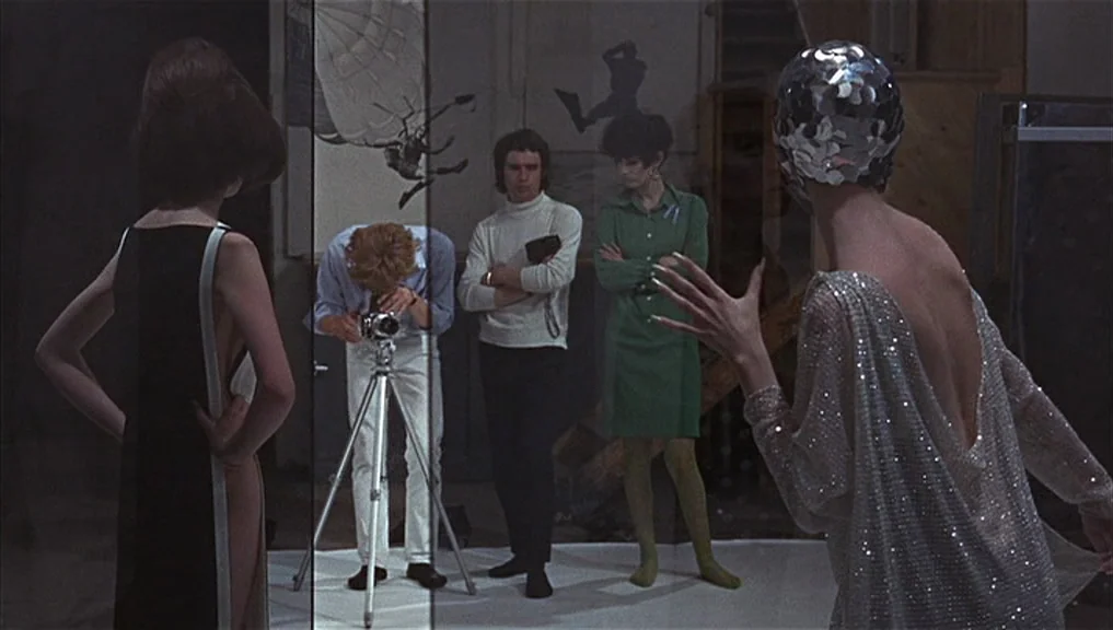 Blow-Up (1966) movie still: wide — A 1960s photo studio with minimalist white backdrop and reflective props. A photographer operates a…