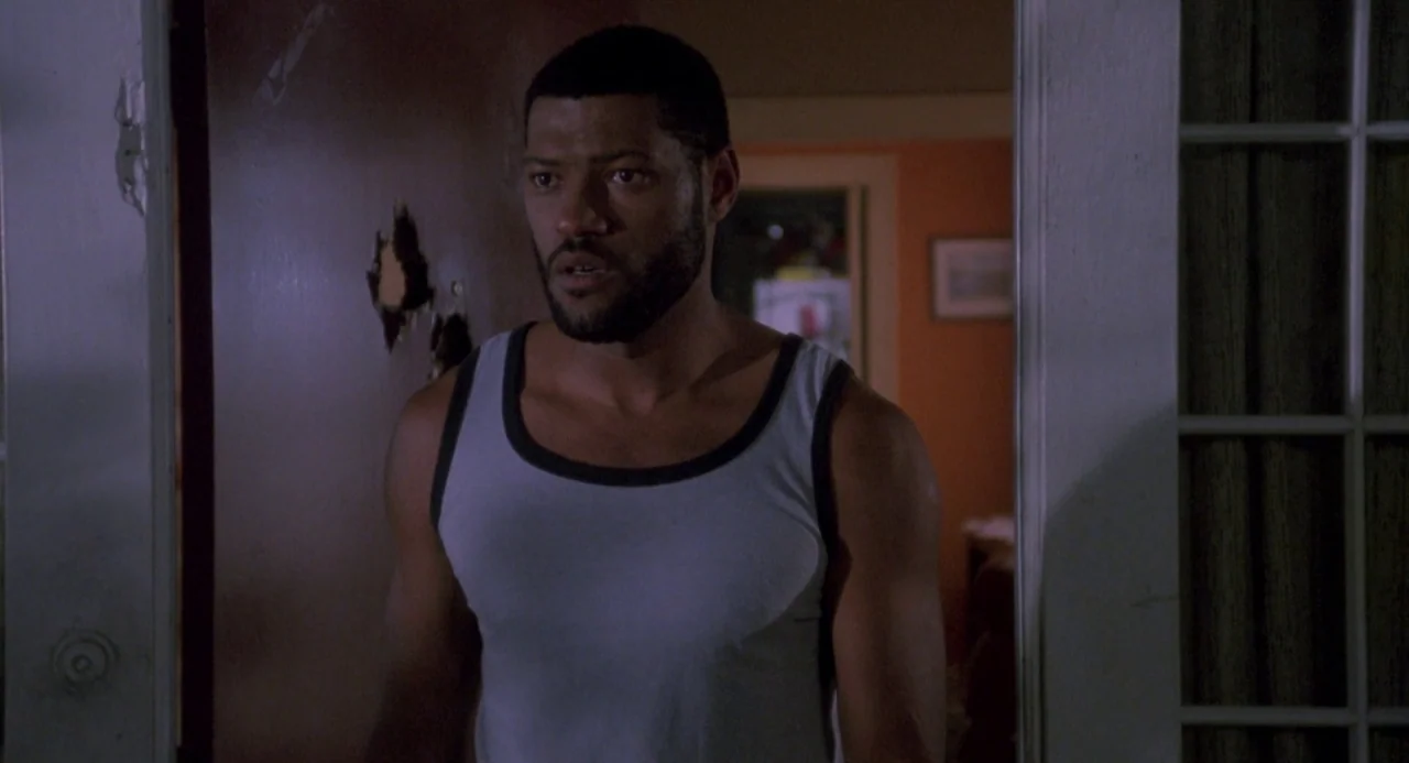 Boyz In The Hood (1991) movie still: medium — A man stands in a door frame with a small patch of damage in the wood. He gazes into an adjacent dimly…