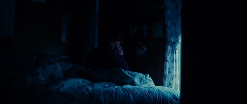 Bubble (2005) movie still: medium — A dark bedroom at night features a bed covered in crumpled patterned linens. A solitary person sits on the bed,…