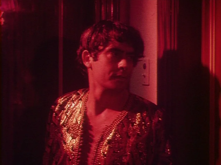 Hermitage (1968) movie still: medium — A man stands in a dark hallway illuminated by deep red lighting. The subject faces right with a blank…
